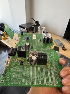 Repaired marine electronic control and power supply PCBs including power supply, digital I/O, and CPU boards undergoing testing after component replacement.