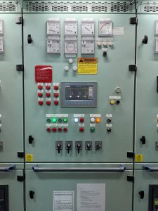 Marine power management system control panel showing load sharing meters, synchronization gauges, alarms, and control switches during inspection and fault recovery.