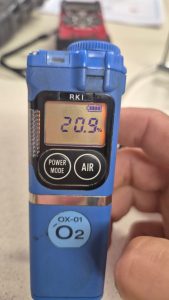 RKI Riken Keiki OX-01 portable oxygen gas detector displaying 20.9 percent O₂ during calibration check in a marine environment.