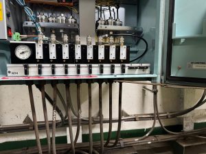 Ballast tank gauging system manifold with flow controllers, pressure gauge, and tank connections under inspection during marine service
