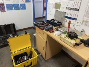 UTI meter repair service workspace on board a tanker ship with calibration tools, test equipment and opened instrument cases during inspection and full function testing.
